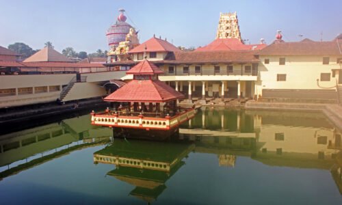 Holy Shrine dedicated to Hindu Deity, Lord Krishna. Picture taken in the town of Udupi, in the state of Karnataka, South India.   Picture shot on Feb 10, 2014, and shows the holy tank in the foreground, with the Temple towers seen in the background.  The building in the center of the tank, known as Mandapam, is where the sacred rituals are carried out. Four pillared corridors surround the tank with steps descending to the water.  This is for the convenience of devotees to take a dip in the holy tank, before entering the Temple. The holy tank here is named Madhava Sarovar, after the local saint Madhavacharya, who preached a form of Hinduism, several centuries ago.